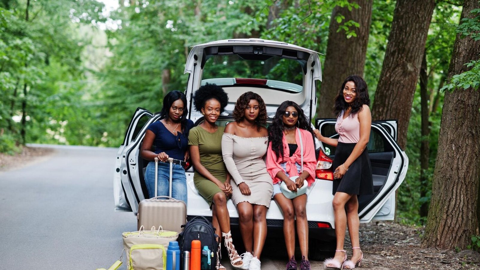 A picture of five girls standing near the boot of a car with bags